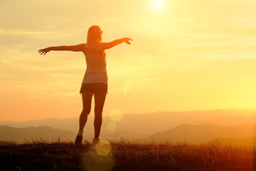 Happy woman with open arms stay on the peak of the mountain 