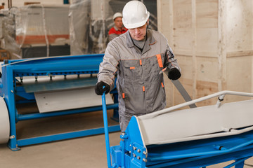 Workers adjusts the machine in the warehouse. the production of ventilation and gutters. Tool and bending equipment for sheet metal. manufacture workshop.