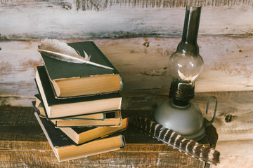 books and oil lamp on the table. wooden background. vintage