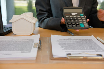real estate agent showing investment price on calculator. realtor with mortgage loan agreement