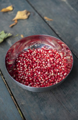 Fresh pomegranate seeds in metal bowl on wooden table