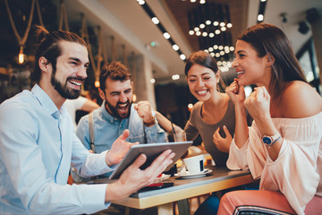 Group of Happy friends having with digital tablet in cafe