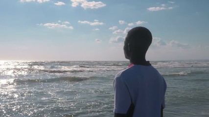 lonely african migrant on the beach contemplating the ocean- slow motion