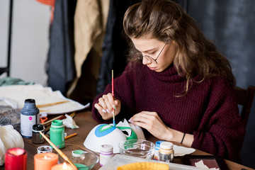 Skilled woman painting mask at table