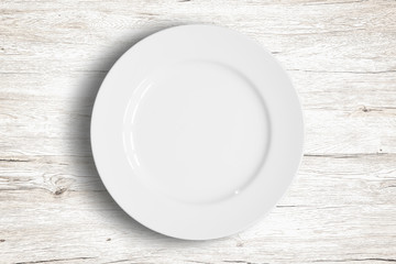 Top view of empty white food dish on a wooden background.