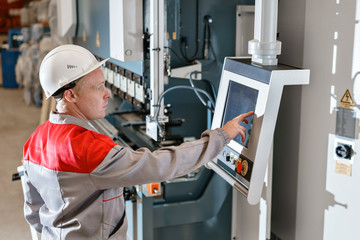 control computer display of Machine. Manufacture workers adjusts the machine in the warehouse. the production of ventilation and gutters. Tool and bending equipment for sheet metal.