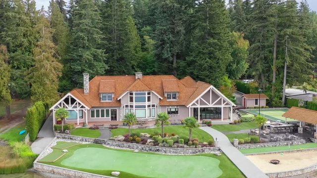 Luxury lake house exterior aerial approach and fly-over; 4k footage