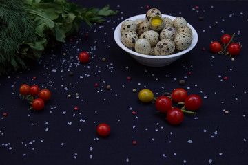 dill, parsley, sorrel and quail eggs in a white plate with tomatoes and sea salt and pepper mixture in a dark background