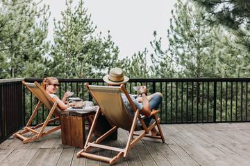 Couple enjoying coffee on a balcony in the mountains - obrazy, fototapety, plakaty