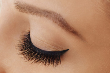 Female eye with extreme long false eyelashes and black liner. Eyelash extensions, make-up, cosmetics, beauty