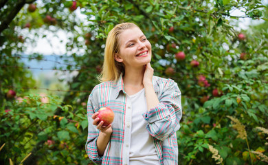 Farmer pretty blonde with appetite red apple. Harvesting season concept. Woman hold apple garden...