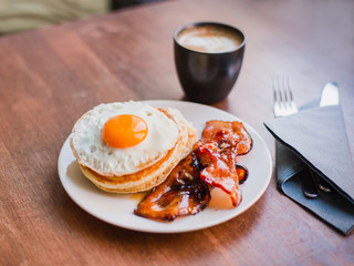 Tasty breakfast with pancakes, fried egg, coffee and bacon