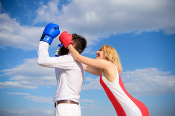 Girl use cunning trick in fight. Couple in love boxing gloves blue sky background. Girl close his...