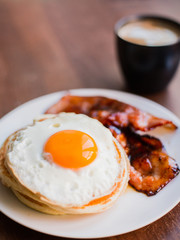 Tasty breakfast with pancakes, fried egg, coffee and bacon