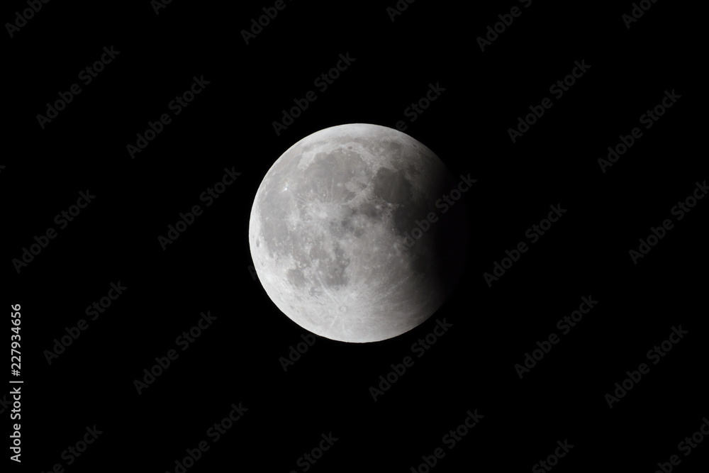 Wall mural super bloody moon, full eclipse last phase against black sky background, small part of moon surface 