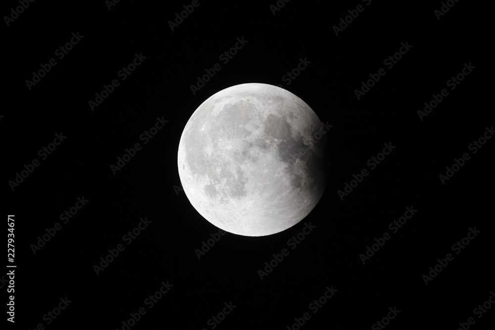 Wall mural super bloody moon, full eclipse last phase against black sky background, small part of moon surface 