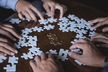 Hands of diverse people assembling jigsaw puzzle, Youth team put pieces together searching for right match, help support in teamwork to find common solution concept, top close up view