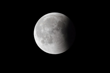 Super Bloody Moon, full eclipse last phase against black sky background, quarter of the Moon surface covered by Earth's shadow