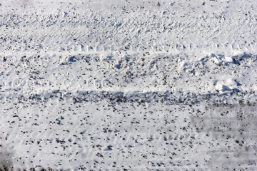Snow with small pebbles on the street. Winter background