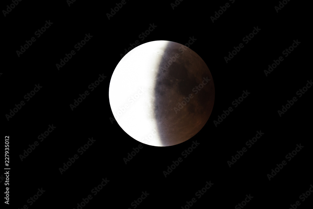 Wall mural super bloody moon, full eclipse end phase against black sky background, half of the moon surface cov