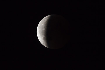 Super Bloody Moon, full eclipse end phase against black sky background, three-quarters of the Moon surface covered by Earth's shadow