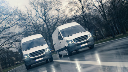 Zwei wei&szlig;e Transporter fahren schnell auf einer nassen Stra&szlig;e