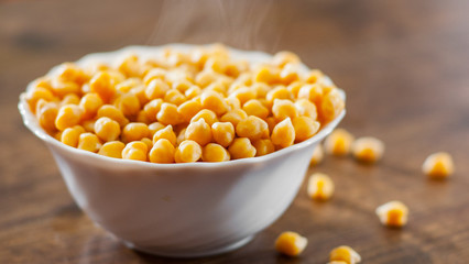 closeup of a bowl with boiled chickpeas on wooden table background