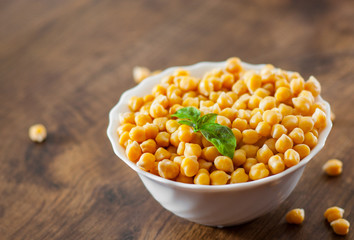 closeup of a bowl with boiled chickpeas on wooden table background