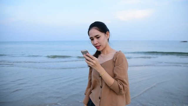 Asian women holding smartphone take photo travel at beach and sea