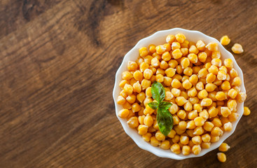 closeup of a bowl with boiled chickpeas on wooden table background
