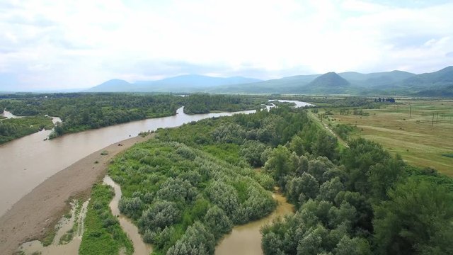 Flight drones over a large river. On the background of beautiful mountains. Flood of water in the mountains and a violent dirty river