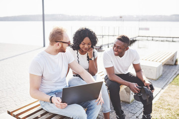 Beautiful multi ethnic friends using a laptop in the Street. Youth lifestyle concept