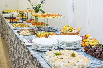 Buffet table of reception with cold snacks, meat and cakes