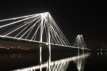 Obraz premium Night illumination on the cable-stayed bridge over the river.