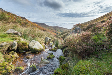 Fototapeta na wymiar Grind's Brook tumbles towards Edale in the Peak District National Park. Known as Grindsbrook Clough it is a popular route for walkers to both Upper and Nether Tor and Grindslow Knoll