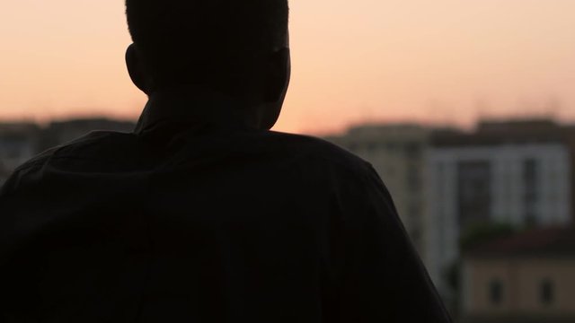 silhouette of young man contemplating the city at sunset