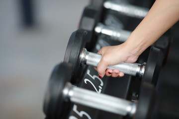 Plakat Woman hand holding a dumbbell in the gym.