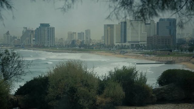 Drops of rain on a window glass. Through the window view of the beach, sea and the resort city in Tel Aviv, Israel, cca 2015.
