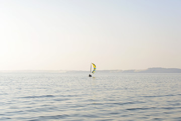 Sailboat with yellow blue striped sail in the sea