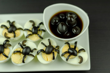 funny snack with olive spiders on egg halves for halloween party, creative food application