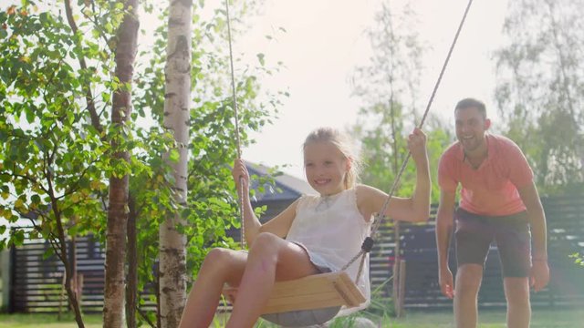 Joyous Father Pushes Swings with His Cute Little Daughter on Them 