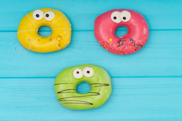 Three colorful iced donuts with eyes