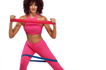 Muscular young fit sports woman athlete in pink sportswear with bands or expander in gym. Copy...