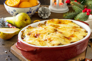 Potato gratin with pear, raclette cheese, and bacon on a festive Christmas table.Traditional french...