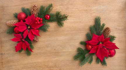 Fototapeta na wymiar Christmas decoration. Frame of flowers of red poinsettia, twigs christmas tree, christmas ball, red berry and cone spruce on a wooden background with space for text. Top view, flat lay