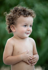 Beautiful baby with curly hair in the garden