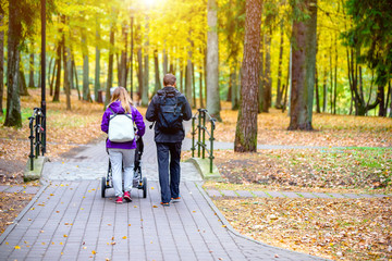 A married couple rolls a baby stroller in a city Park