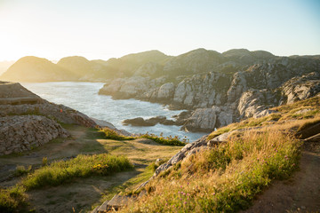 Serene scandinavian summer landscape on south coast of Norway. Rocky Mountains, fjord from top. Sunset sky. Lindesnes