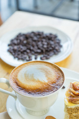Hot coffee late in white cup on blurred raw coffee seed background,
