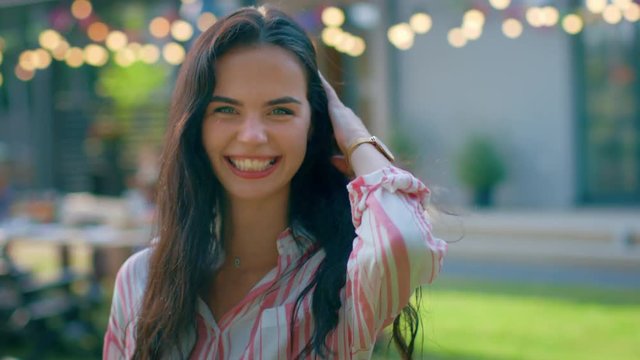 Portrait of Beautiful Brunette with Loose Hair Charmingly Smiling, Straightening Her Hair